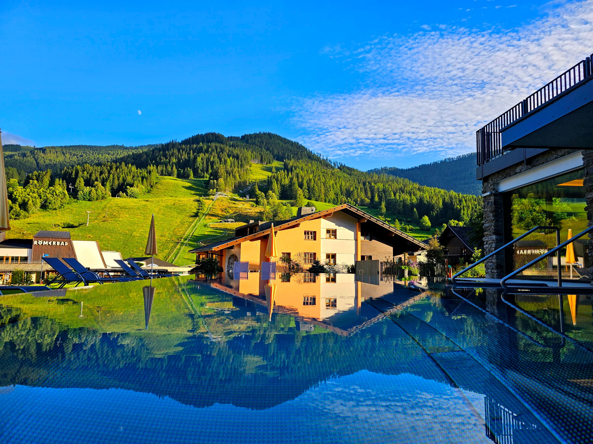 Freiluftpool umgeben von Berglandschaft mit angrenzendem Gebäude für Wellness-Urlauber