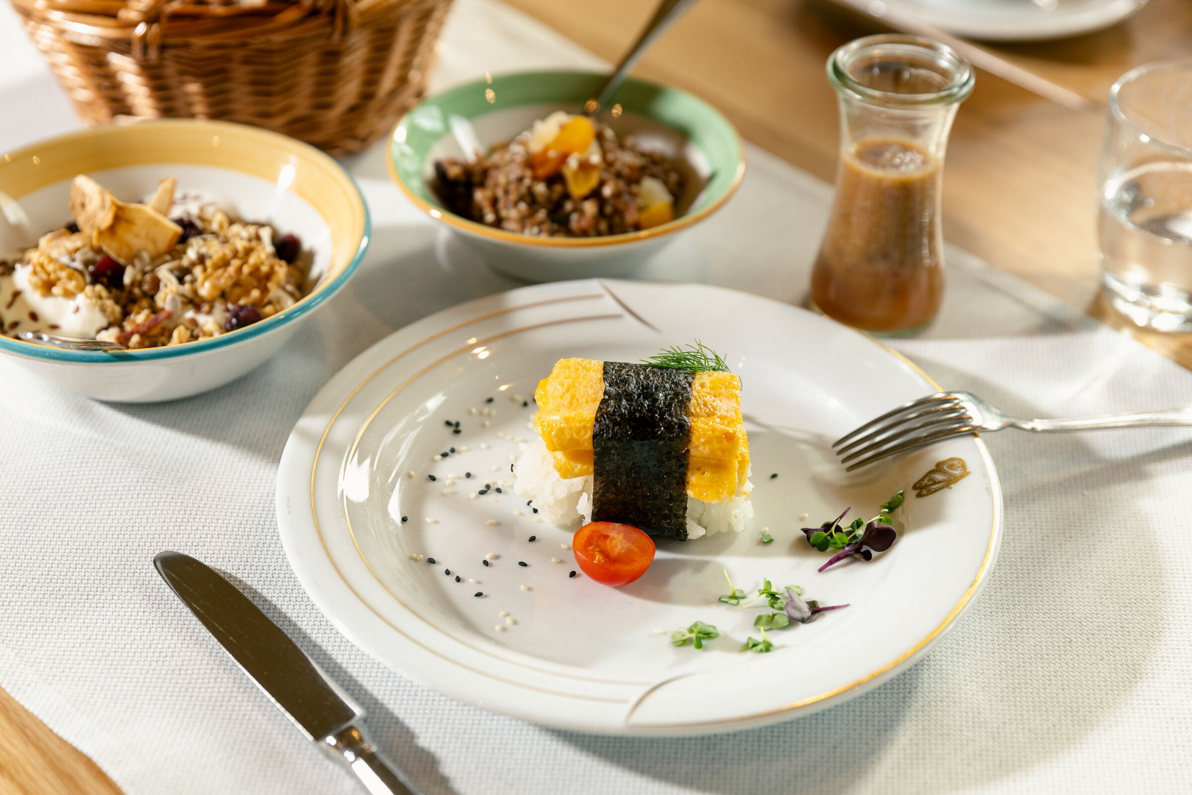 Ein kunstvoll angerichtetes Sushi-Gericht mit Beilagen und Dressing in einem Glas.