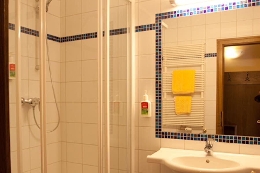 Helles, modernes Badezimmer mit Dusche und Handtüchern in einem Wellnesshotel, ideal für Entspannung.