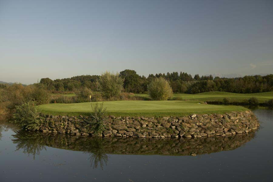 Landschaft mit Golfplatz umgeben von Wasser und üppiger Vegetation zur Förderung der Entspannung.