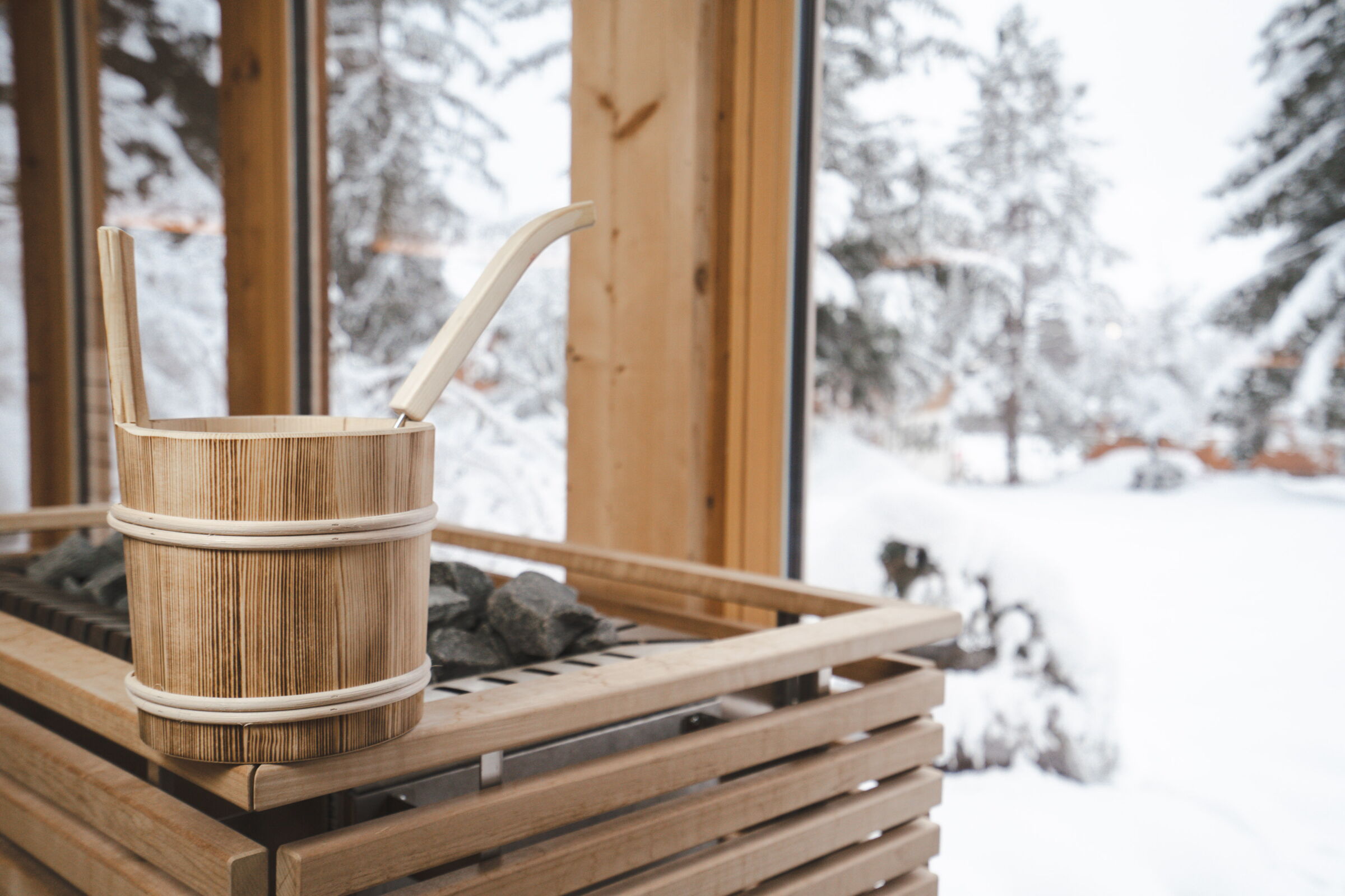 Holzfass mit Aufguss auf einem Saunabereich und Blick auf die winterliche Landschaft