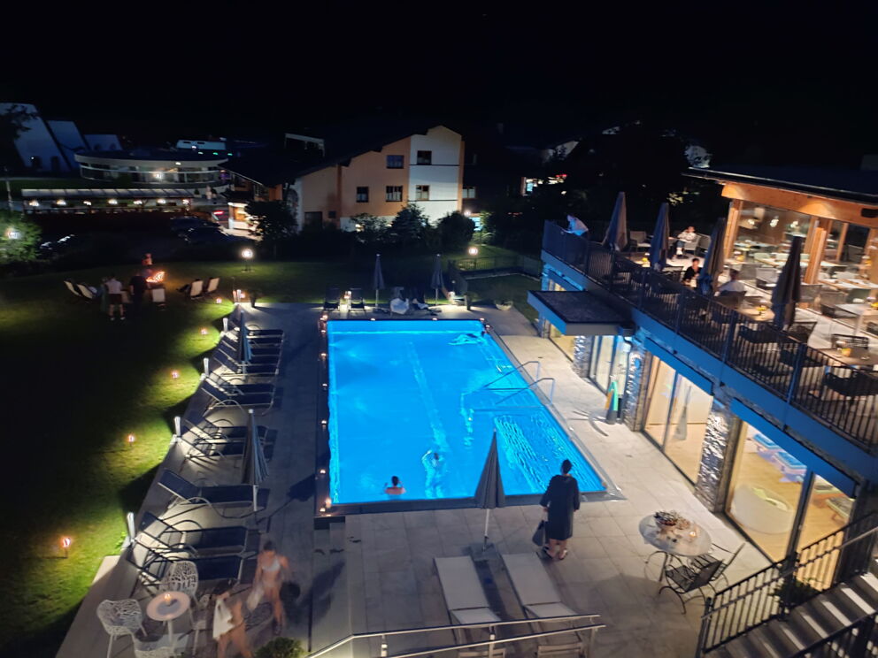 Spa-Bereich mit beleuchtetem Pool und Liegen für entspannte Abende unter freiem Himmel.