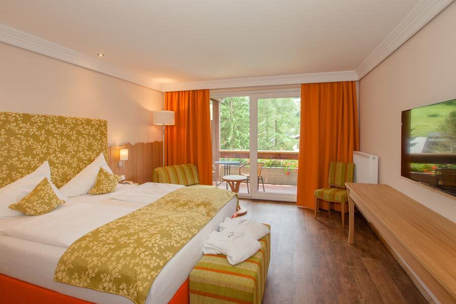 Wohlfühlbereich im Spa Zimmer mit Doppelbett und gemütlicher Sitzecke vor großen Fenstern